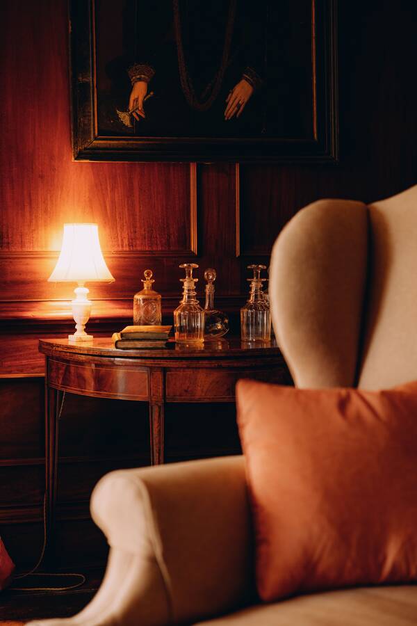 A wing chair and lamp in a panelled room at The Salwey Lodge near Ludlow