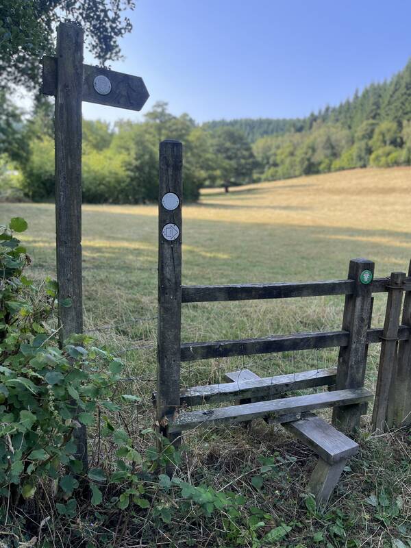 A wooden stile and footpath sign on a walk from The Salwey Lodge near Ludlow