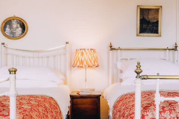 Twin brass beds and patterned lamp in a guest bedroom at The Salwey Lodge near Ludlow